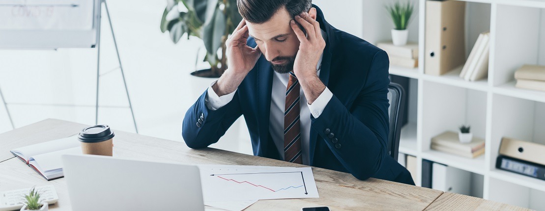 Man looking at chart and holding his head