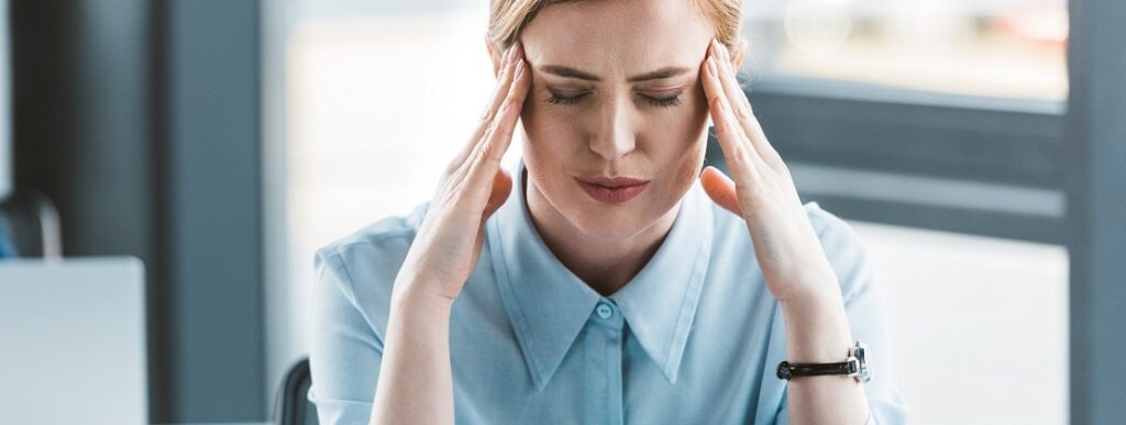 Woman looking at a computer holding head