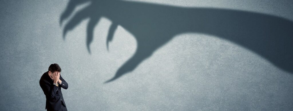 A businessman afraid of a hand shaped shadow