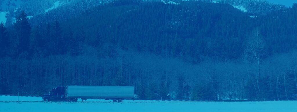 A freight truck moving by a mountainside