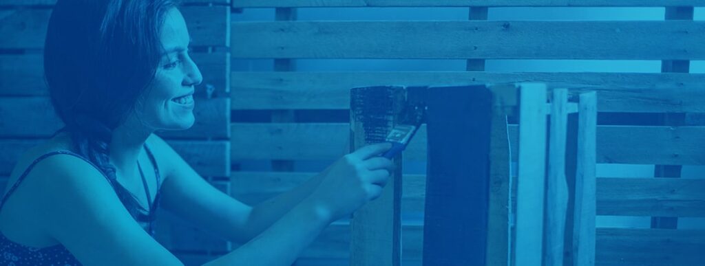 A woman painting a pallet in black paint