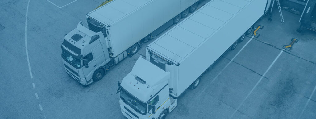 Two freight trucks parked at a loading dock