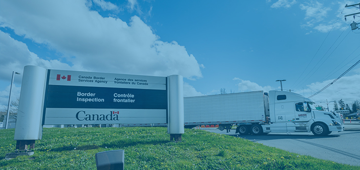 A Canada Border Security billboard with a freight truck behind it.